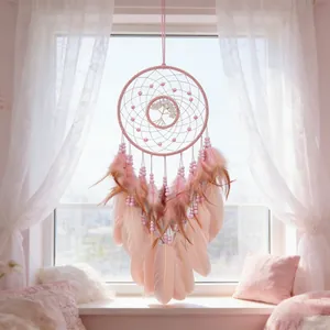 Elegant pink dream catcher with tree of life design and soft feathers hanging in a window