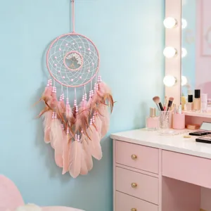 Pink Tree of Life dreamcatcher with soft feathers hanging in a cozy bedroom setting