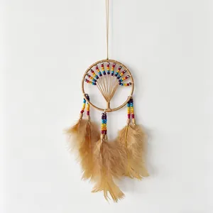 Detailed view of handmade dreamcatcher with rainbow beads and soft brown feathers.