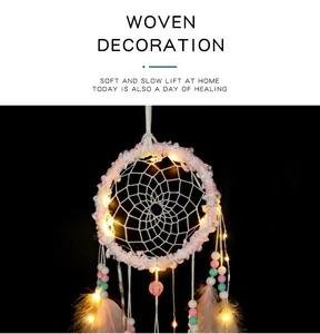 Vue détaillée d'un attrape-rêves rose avec des lumières LED et des plumes douces