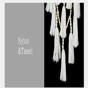 Close-up detail of soft white nylon tassels and wooden beads on Nordic wall decor