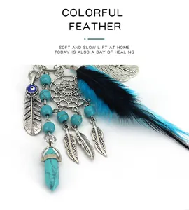 Close-up detail of Indian dreamcatcher keychain with feathers and turquoise beads.