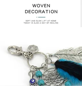 Detailed close-up of Indian dreamcatcher keychain with feathers and evil eye charm.
