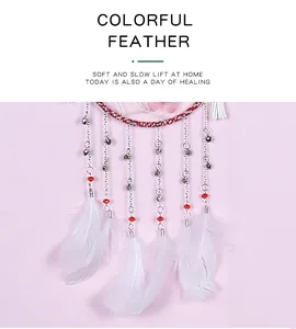 Close-up detail of soft white feathers and silver chains on dreamcatcher ornament