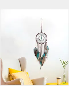 Attrape-rêves style bohème avec pierre turquoise et plumes bleues sur un mur blanc
