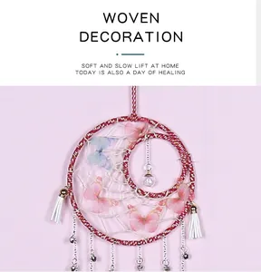 Detailed view of a pink handmade butterfly dreamcatcher with tassels and bells decoration