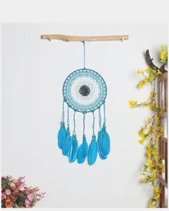 Atrapasueños azul con plumas y motivo de ojo turco colgado en una vara de madera.