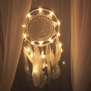 Atrapasueños de encaje bohemio con plumas y luces LED cálidas colgado en cortinas