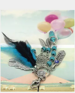 Close-up of bohemian dreamcatcher keychain featuring feathers and turquoise beads.