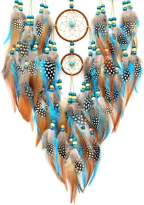 Dettaglio di acchiappasogni boho con piume blu e maculate per decorazione da parete