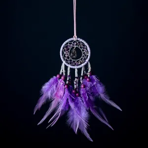 Detalle de atrapasueños morado con piedras naturales y plumas suaves decorativas