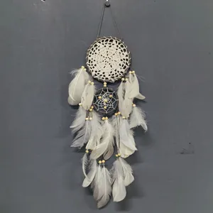 Detalle del atrapasueños blanco bohemio con red de ganchillo y plumas naturales.