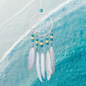 Mini atrapasueños blanco para coche con cuentas azules y plumas sobre fondo de océano azul