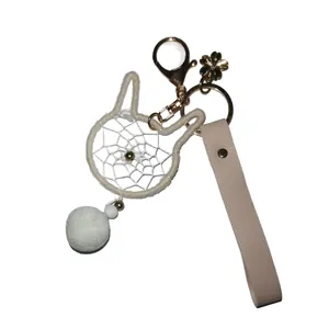 Cute cat-shaped dreamcatcher keychain with white pom-pom and beige leather strap