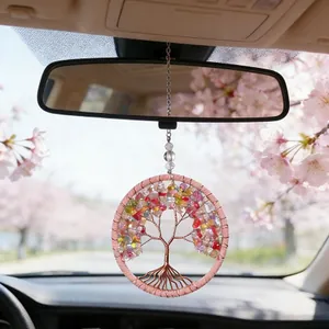 Detailed view of pink crystal tree of life car hanging charm in cherry blossom setting