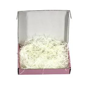 Caja de regalo de cartón rosa con relleno de papel triturado blanco para empaquetar.