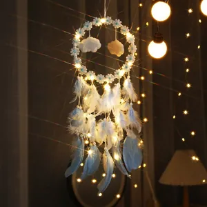 Detalle de un atrapasueños iluminado con plumas azules y flores blancas decorativas