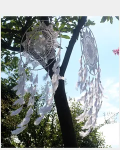 Detalle de atrapasueños nórdicos blancos colgados de una rama de árbol verde