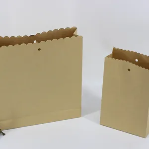 Umweltfreundliche braune Kraftpapiertüten mit gewelltem Rand und gestanzten Grifflöchern