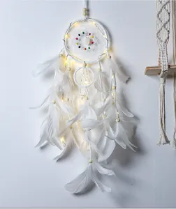 Detailweergave van een witte dromenvanger met warme LED-verlichting en witte veren.