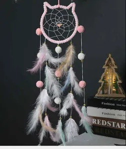Atrapasueños con forma de gato con pompones rosas y plumas en un ambiente acogedor