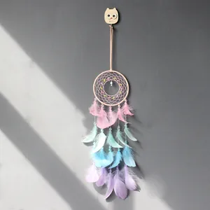 Détail d'un attrape-rêves aux couleurs pastel avec des plumes sur un mur gris