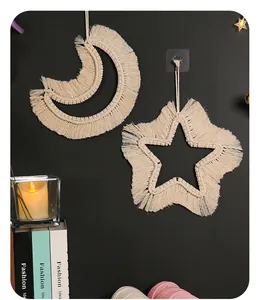 Detalle del tapiz de pared bohemio de macramé con forma de luna y estrella.