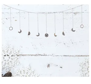 Bohemian iron moon phase wall hanging garland decoration on white wood background.