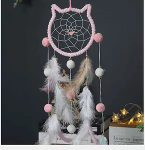 Vista detallada de un atrapasueños rosa con forma de gato, plumas y pompones suaves