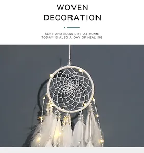 Primer plano de un atrapasueños tejido blanco con luces LED cálidas y plumas suaves