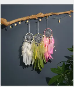 Vista detallada de tres atrapasueños con luces LED colgados de una rama de madera