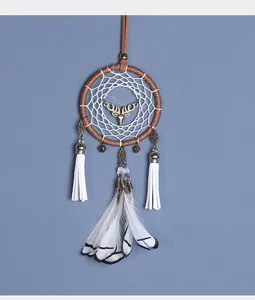 Detail van een witte dromenvanger met een hertenkop hanger en elegante veren