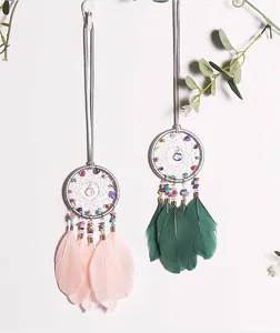 Close-up of handmade dreamcatchers featuring colorful crushed stones and soft feathers