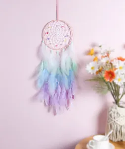 Atrapasueños hecho a mano con plumas degradadas pastel colgado en una pared rosa