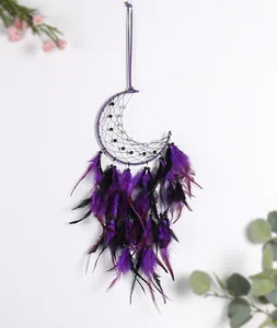 Detail view of a handmade crescent moon dream catcher with purple and black feathers.