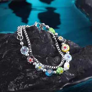 Detailansicht eines doppellagigen Armbands mit bunten Millefiori-Glasperlen auf Stein.