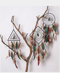Detailed view of handmade geometric dreamcatchers with natural feathers on branch
