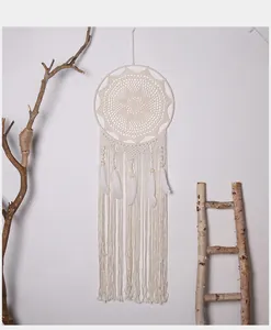 Grote handgemaakte macramé dromenvanger met witte veren aan de muur