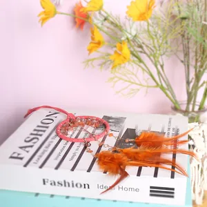 Vintage Tree of Life dromenvanger met natuurstenen en oranje veren op een modeboek