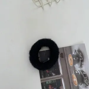 Nahaufnahme eines schwarzen, flauschigen, gestrickten Haargummis auf weißem Hintergrund