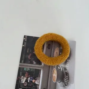 Detailaufnahme des senfgelben gestrickten Haargummis auf dekorativem Postkartenhintergrund