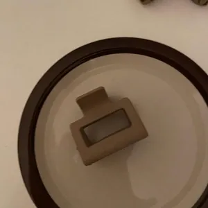 Vista dettagliata di un fermaglio geometrico beige opaco su un vassoio minimalista