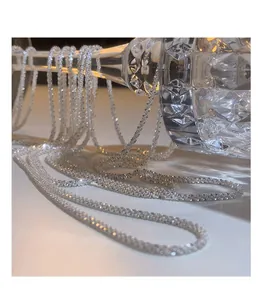Detailed close-up of shimmering silver star chain necklace draped over crystal glass.