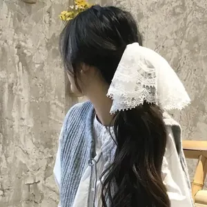 Close-up detail of a French elegant white lace bow hair clip worn on long wavy hair.