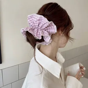 Close-up detail of a large pink plaid scrunchie hair tie styled in a woman's bun