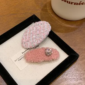Détail des barrettes en tweed rose et peluche avec strass en forme de cœur étincelant