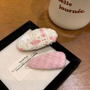 Vue rapprochée détaillée de barrettes pour filles en tweed rose et tissu fleuri tissé