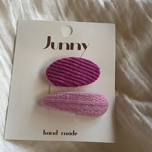 Détail de barrettes à cheveux en velours côtelé rose et tricot sur carte blanche.