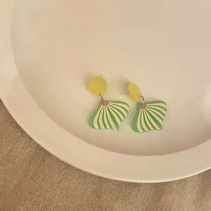 Close-up of quirky green and yellow striped acrylic fan-shaped drop earrings for women