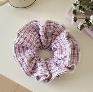 Detail view of the pink plaid fabric texture on a soft elastic hair scrunchie